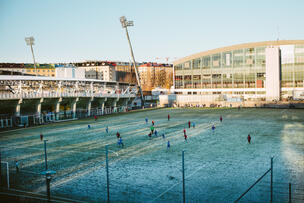 Young people playing football on a frosty lawn.