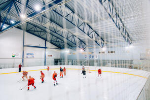 Red-clad players in a hockey game in an ice rink.