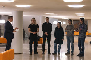 Jolkkonen puhuu viidelle palkittavalle ohjelmistosuunnittelijalle tyylikkäässä aulassa. 