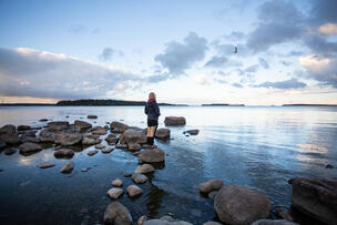 Ihminen seisoo rantakivellä veden ääressä.