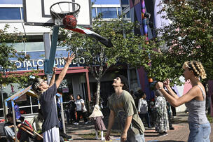 Kolme ihmistä pelaa koripalloa Kontulan ostarilla.