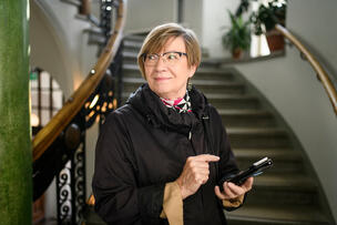 Nainen seisoo puhelin kädessään.