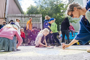 Lapset piirtävät katuliiduilla.