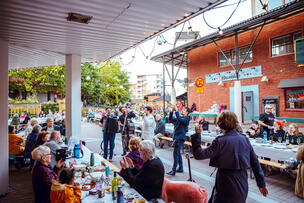 Bändi esiintymässä ja ihmisiä kuuntelemassa Malminkartanon yhteisöllisellä illallisella.