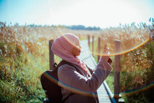 En kvinna fotograferar i naturen.