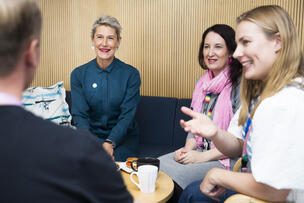 Fyra personer diskuterar vid kaffebordet.