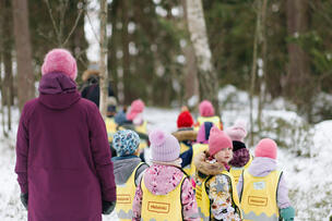 Kuvassa päiväkotilapsia ja aikuinen lumisessa metsässä