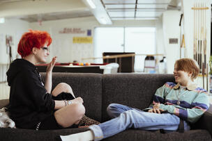 Kaksi nuorta istuu rennosti sohvalla juttelemassa.