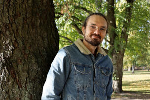 Topi, the father of the foster family, leans against a tree.