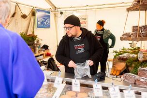 A salesperson wearing a black beanie behind the fish counter.
