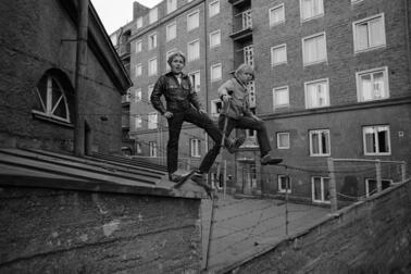 Två killar som står på ett taggtrådsstaket mellan gårdarna i Torkelsbacken i Berghäll, 1970. 
 Bild: Simo Rista / Helsingin kaupunginmuseo