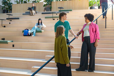 Three people are talking on the staircase.