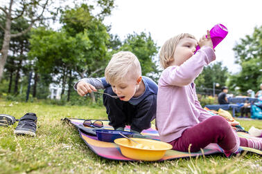 Two kids have lunch at the playground.