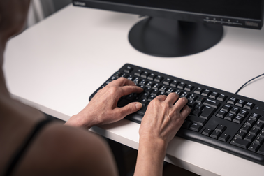 Hands typing on a computer keyboard.