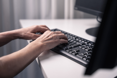 Hands writing on a computer keyboard.