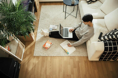  A person is sitting on the floor with a computer.