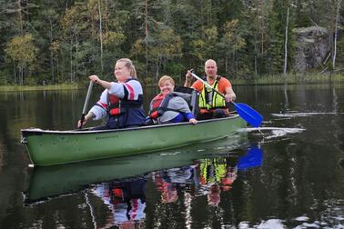 Kolme ihmistä soutaa kanootilla järvellä