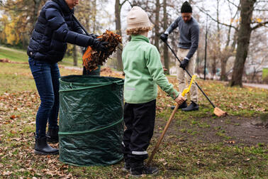 child with their family raking in the Kaivopuisto park.