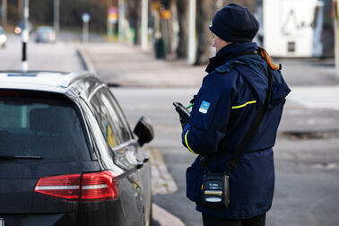 Pysäköinninvalvoja tarkastamassa pysäköityä autoa.