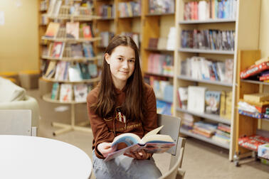 Vera Nylund sitter i Norsens skolbibliotek och bläddar i en bok.