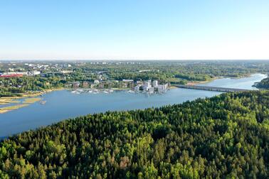 Havainnekuvassa näkyy merenlahti, jonka etualalla on metsää ja takana on rakennuksia sekä venesatama.