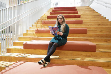 Sanna Pirttinen istuu lukemassa portailla.