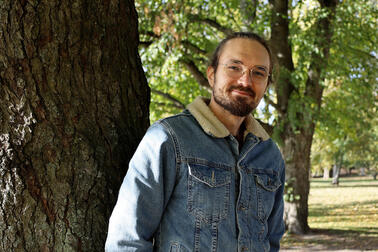 Sijaisperheen isä Topi nojaa puuhun.