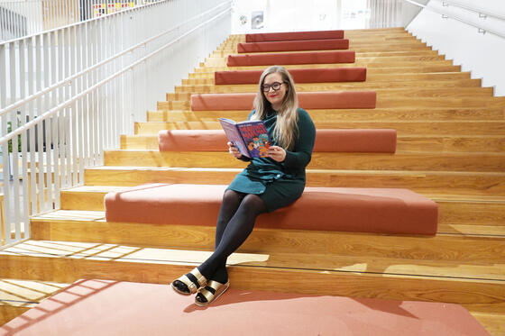 Sanna Pirttinen istuu lukemassa portailla.