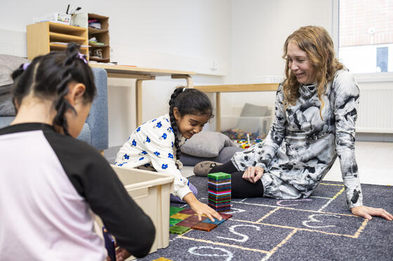 Two children and teacher playing on the floor