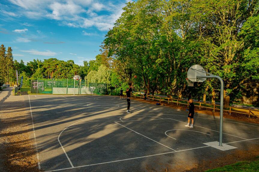 Två personer kastar basketboll på en utomhusplan.