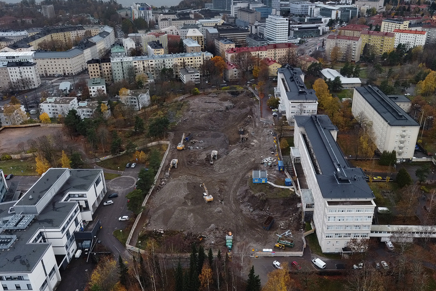 Ilmakuvassa lokakuinen työmaa, kerrostaloja ja puita