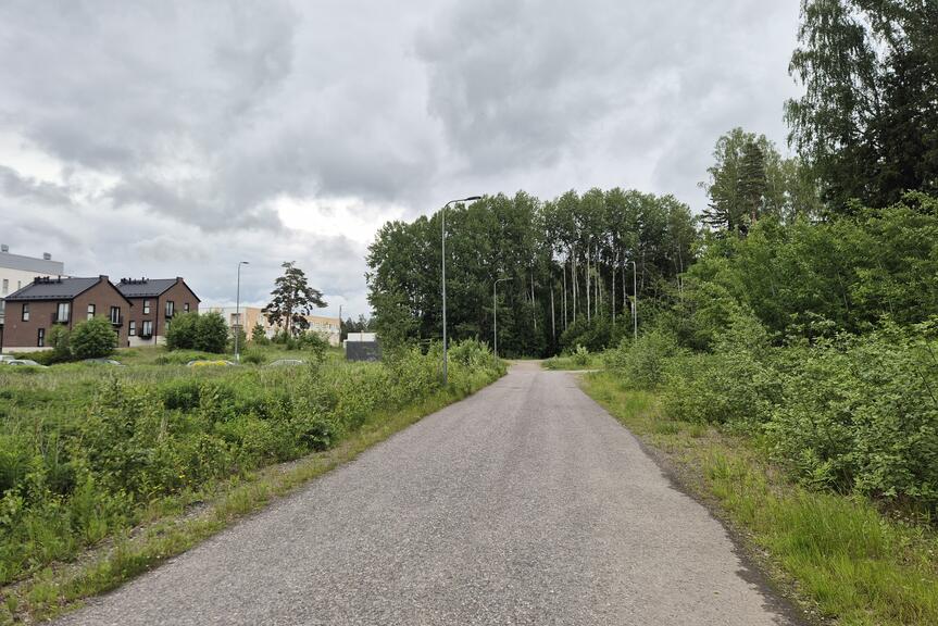 Tie, jonka vasemmalla puolella tyhjiä tontteja. Taustalla matalia kerrostaloja.