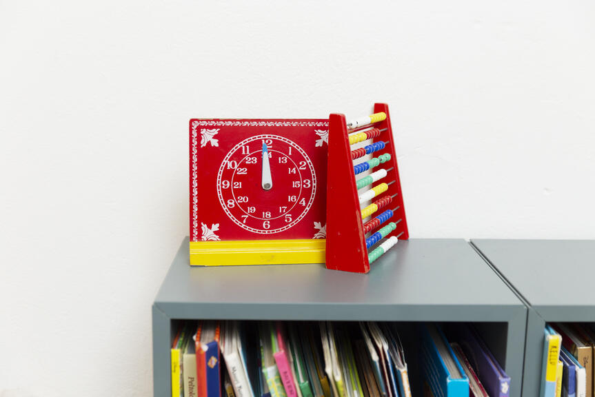 Hyllyllä neuvolan leluja kuten kello ja helmitaulu.