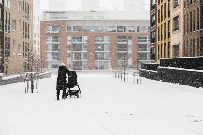 Nainen lumessa lastenrattaiden kanssa