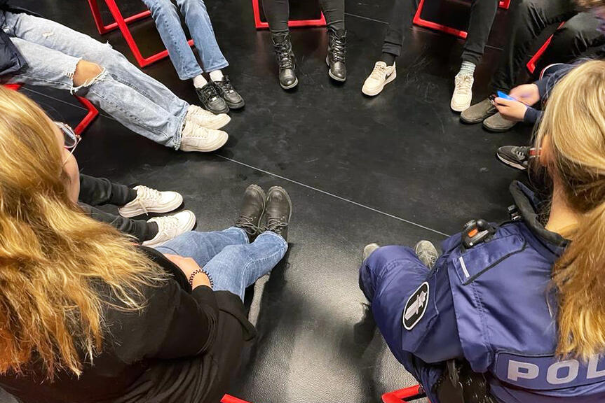 Jalkoja ringissä, ihmisiä istumassa tuoleilla.