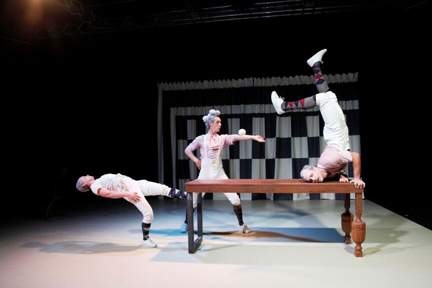 Kolme esiintyjää tekee akrobatiaa lavalla.