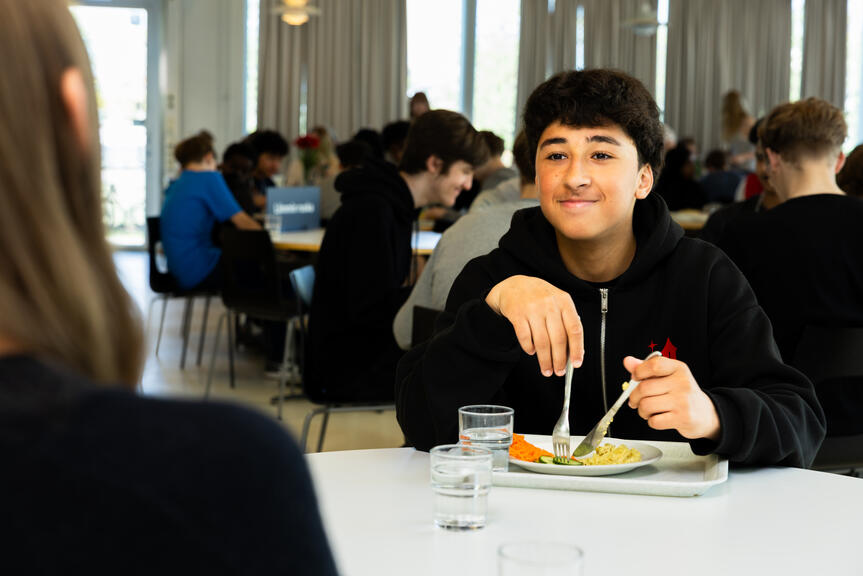 Poika ruokailemassa kouluruokalassa.