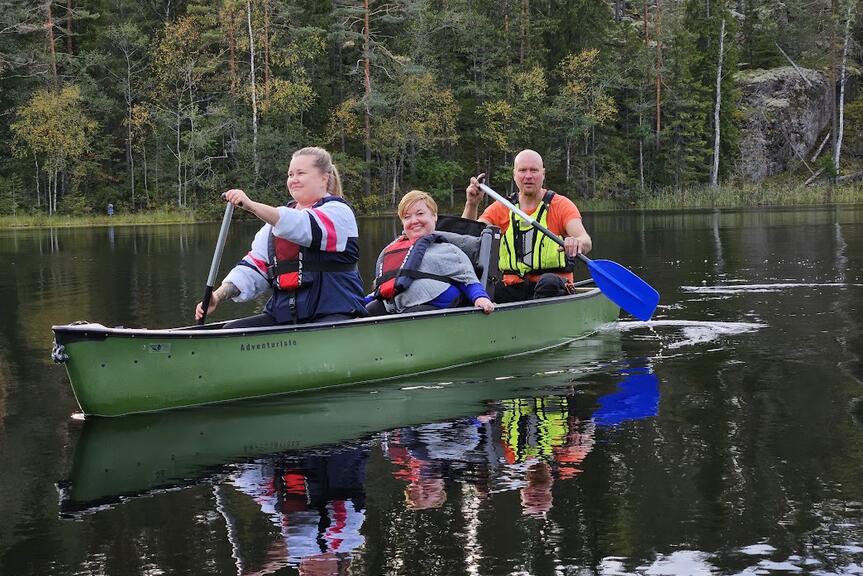 Kolme ihmistä soutaa kanootilla järvellä