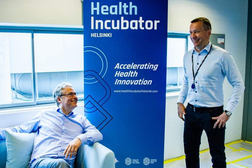 Kaksi henkilöä Health Incubator Helsinki -kyltin edesä.