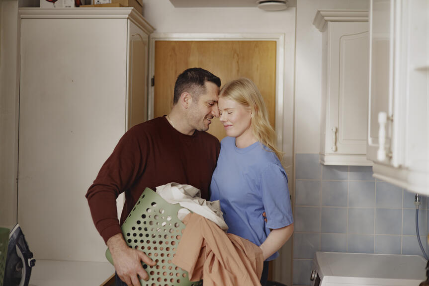 Pariskunta pitää yhdessä pyykkikoria.