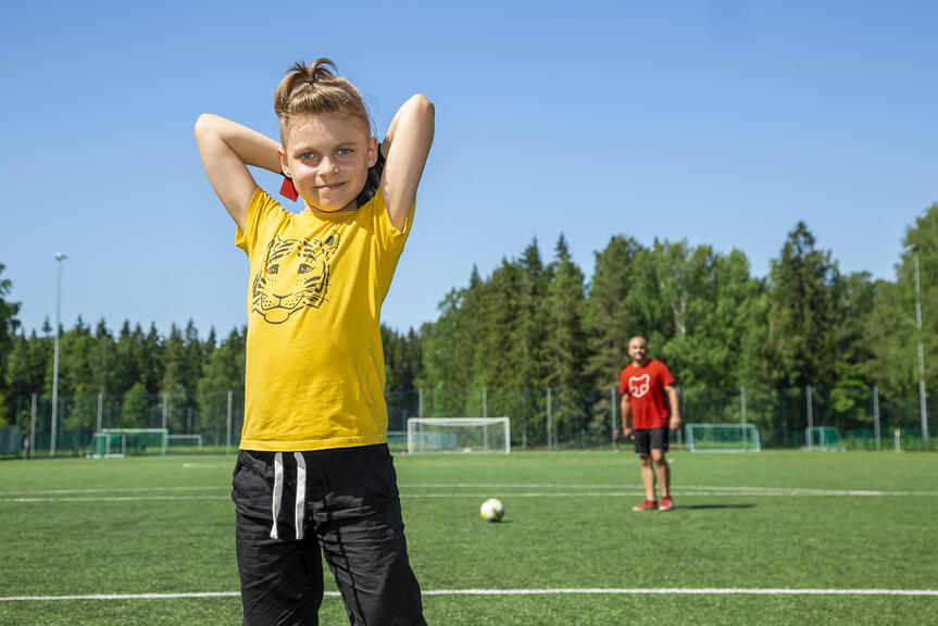 Jalkapallokentällä poika ja aikuinen.