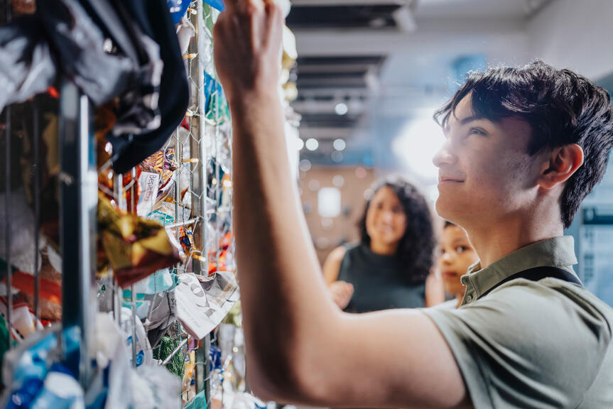 Nuori katsoo roskilla täytettyä seinää näyttelyssä, jossa pohditaan kuluttamista ja kierrättämistä.