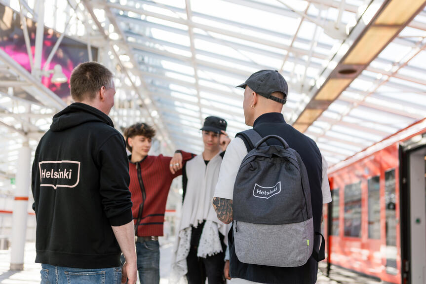 Neljä nuorta seisoo metroasemalla juttelemassa.