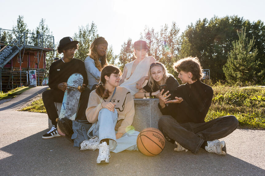 Ryhmä nuoria istuskelee ja juttelee auringonpaisteessa.