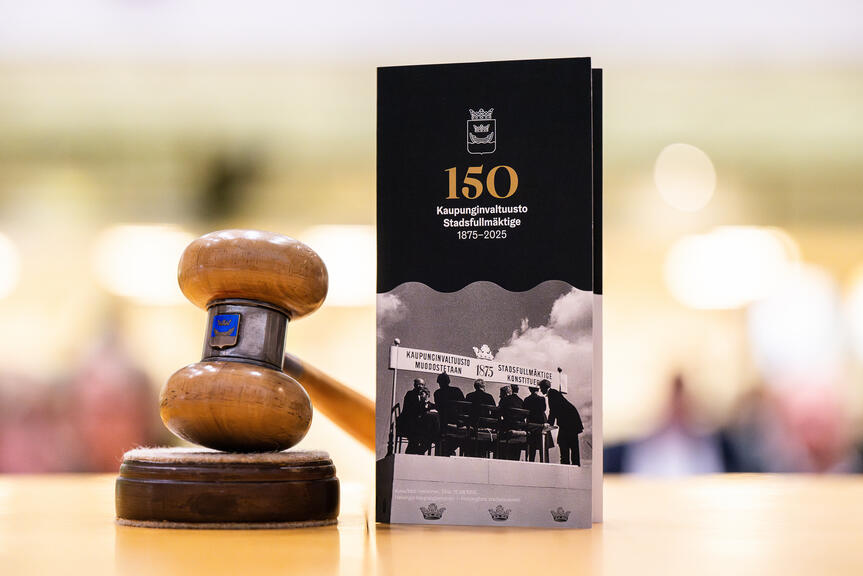 Valtuuston puheenjohtajan nuija sekä juhlavuoden esite pöydällä