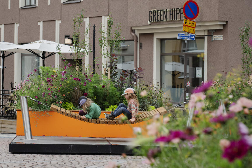 Lapsia riippukeinussa kesäkadulla.