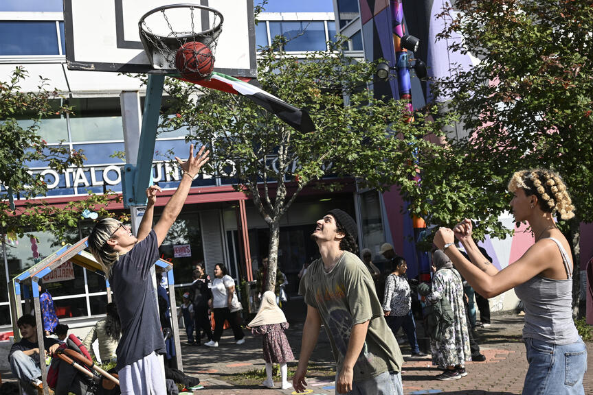 Kolme ihmistä pelaa koripalloa Kontulan ostarilla.