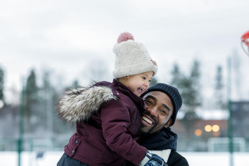 Isä ja lapsi talvisessa leikkipuistossa.