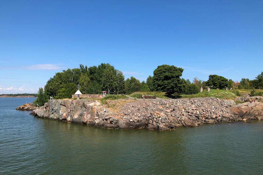 Rocky seashore, trees in the background.