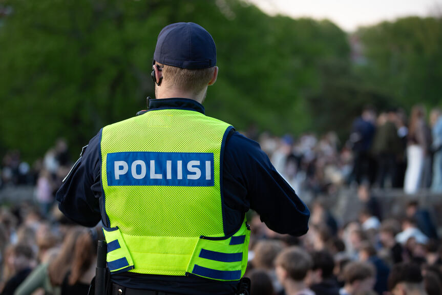 Etualalla poliisi selin kameraan. Taustalla ihmisiä.